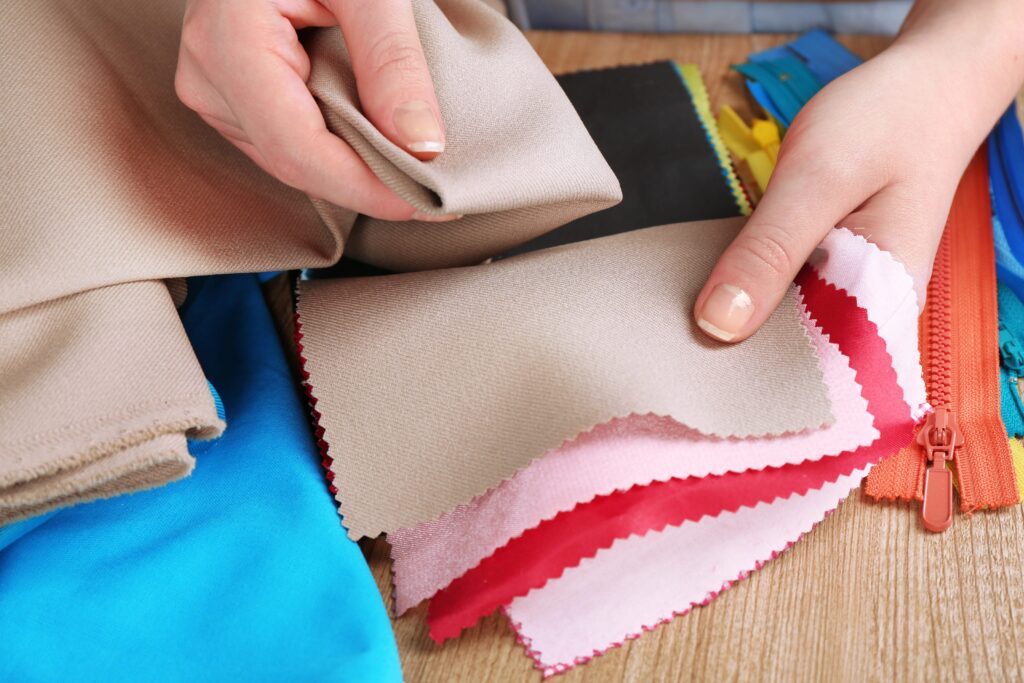 Eine Hand fühlt an verschiedenen Stoffmustern, um die Textur vor der Auswahl zu überprüfen.